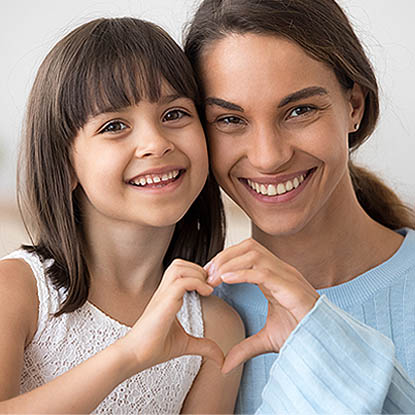 a young girl and her mother holding hands in the shape of a heart